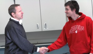 Zach Mellon is congratulated by Activities Director Tom Bauman after signing his Letter of Intent for Wisconsin. Photo by Matt Ebeling